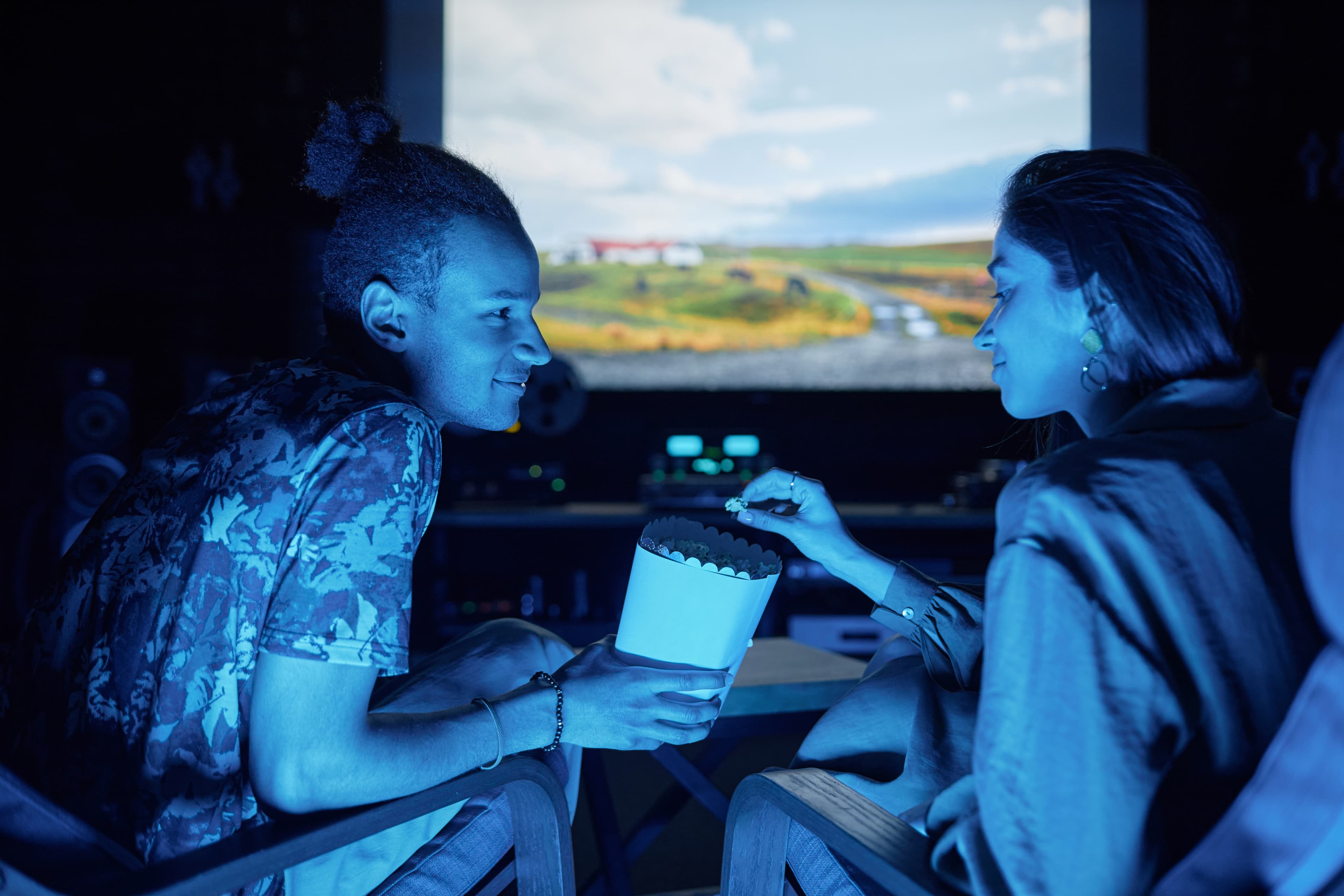 Couple sharing popcorn while watching a movie at a drive-in theater